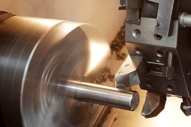 CNC lathe machine turning a metal shaft with high-speed rotation