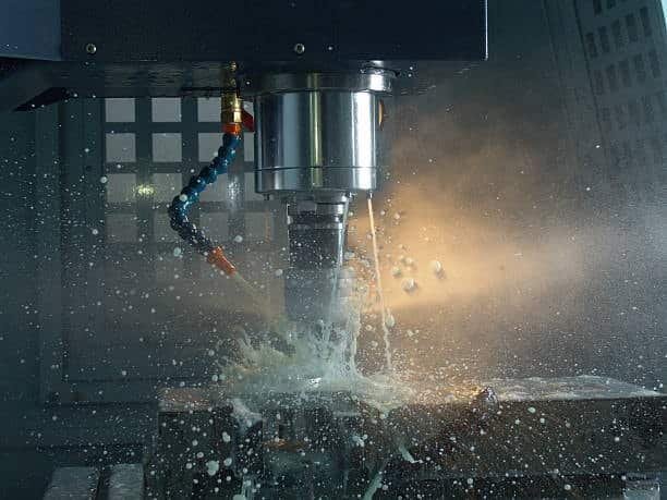 CNC machining operation showing fast tool movement and coolant splashing during metal cutting