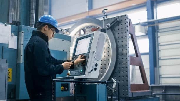 Engineer operating a CNC control panel to set up a large-scale milling machine
