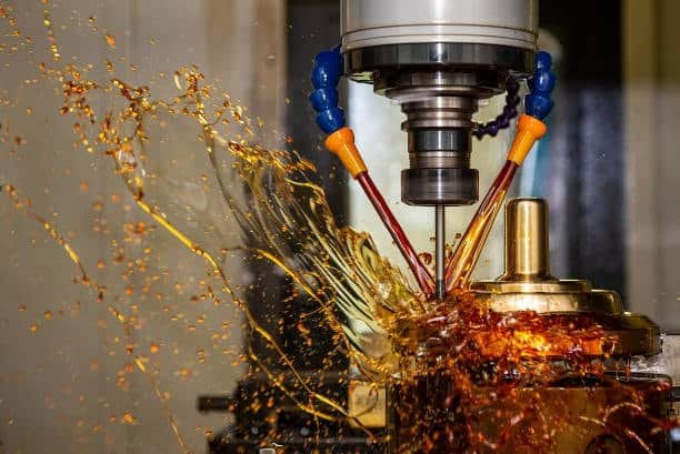 CNC vertical machine spraying oil-based cutting fluid on rotating metal part