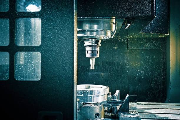 Industrial CNC milling machine cutting an ABS plastic workpiece in an enclosed setup