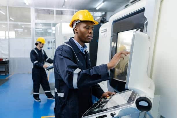 CNC machine operator programming a job using the control interface