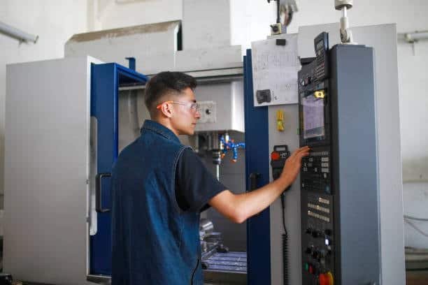 Young technician operating a CNC vertical milling machine in a modern workshop