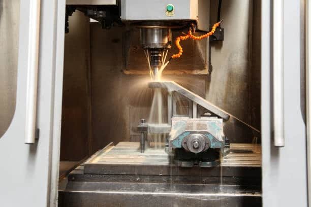 Vertical CNC machine performing automated cutting process in enclosed machining area
