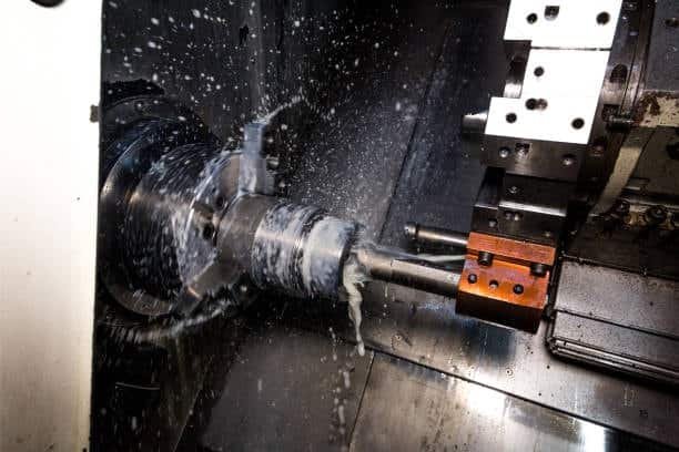 High-speed CNC lathe with heavy coolant spray during turning operation