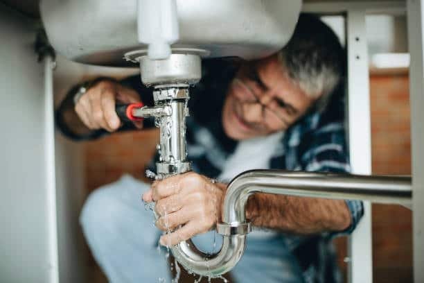 Technician working on pipe fixture design for plumbing system under sink