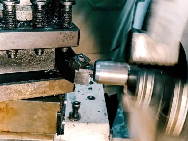 Metal shaft being turned on a lathe with sharp cutting tool