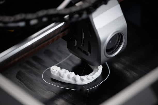 Close-up of a 3D printer fabricating a dental impression using biocompatible material.