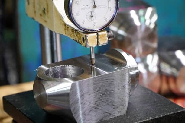 Dial gauge measuring flatness of machined metal part
