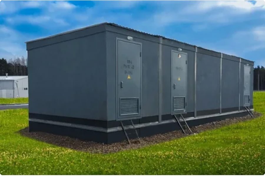 Large outdoor energy storage container units installed on a grassy field under a blue sky, showcasing a battery storage system.