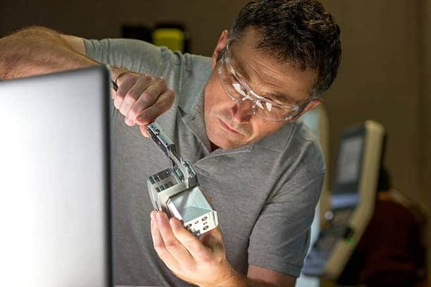 Engineer measuring CNC component to ensure dimensional tolerance accuracy