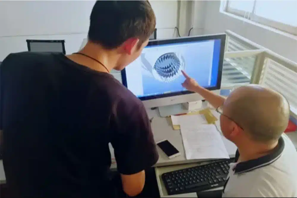 Two mold design engineers collaborating on a CAD model of an intricate injection mold component.