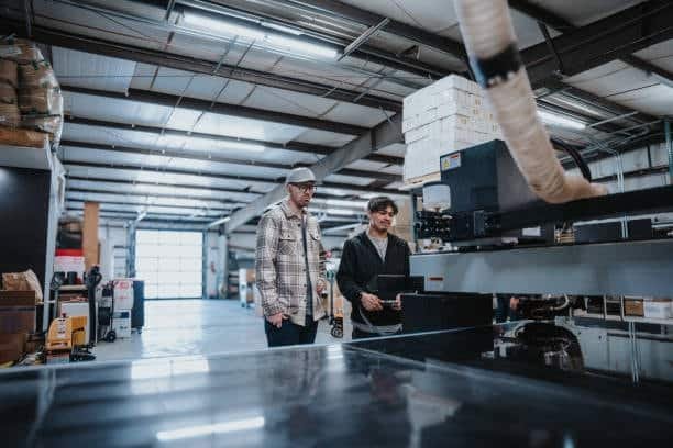 Workshop engineers inspecting CNC machine to ensure correct machining design parameters