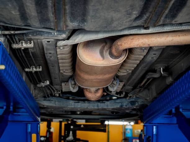 Underside view of vehicle on lift with fixture setup for exhaust system testing