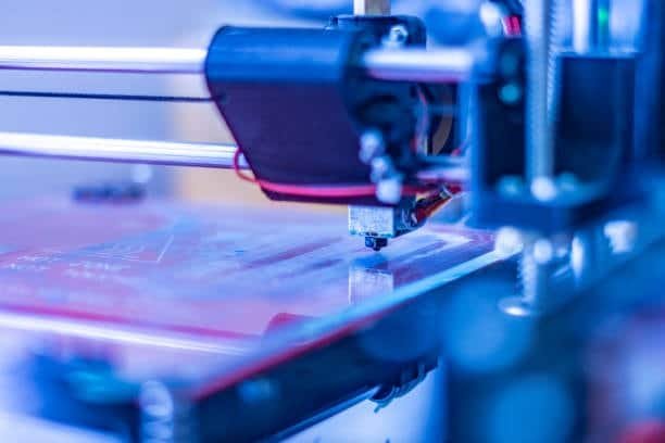 Detailed view of an FDM printer nozzle extruding melted filament onto the print bed.