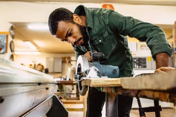 Man carefully aligning a circular saw to cut material with precision in workshop