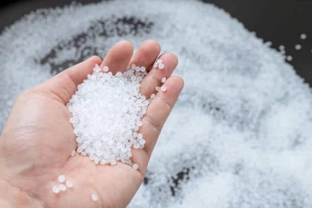 A hand holding translucent polypropylene pellets, highlighting BPA-free, food-safe properties.