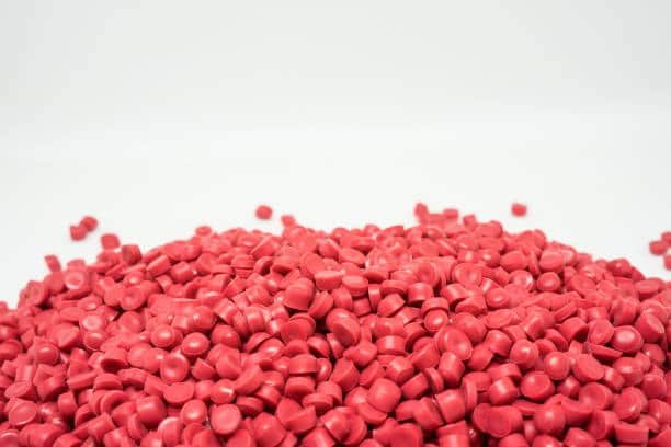Green and red TPE granules on a white surface, representing phthalate-free and food-grade plastic options.