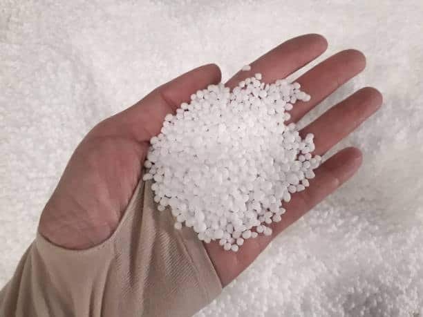 White HDPE plastic granules shown in hand for processing and temperature testing