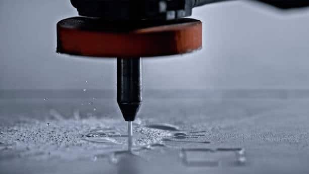 Close-up of CNC waterjet cutting machine slicing through metal sheet