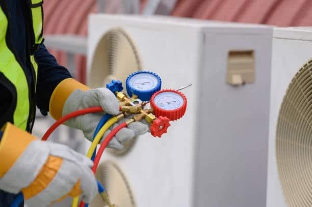 Technician holding manifold gauges to calibrate HVAC fixture connections