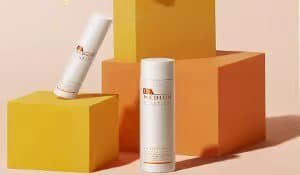 Two sleek injection-molded cosmetic packaging bottles displayed on yellow and orange blocks, showcasing ergonomic design and premium finish.