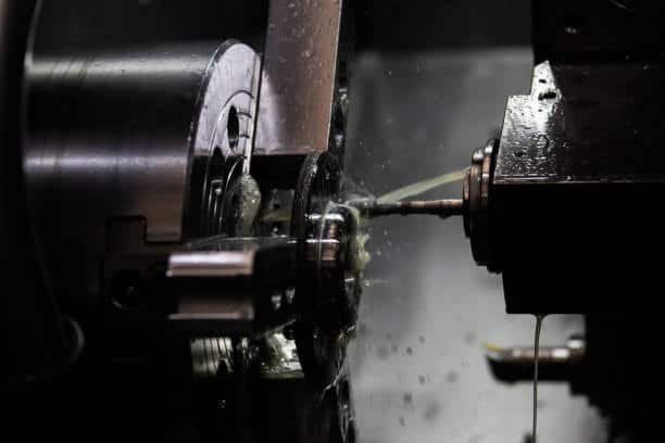 CNC lathe machine performing internal turning with lubricant spray