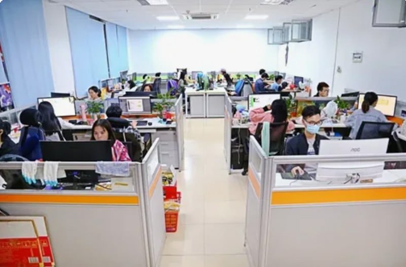 Engineers and designers working in an open-plan office, collaborating on electronic plastic enclosure projects.