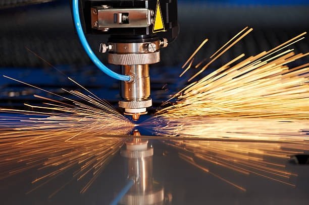 Laser cutter generating sparks while cutting a sheet metal surface