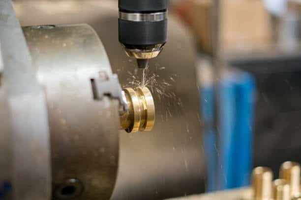 CNC lathe drilling a brass component while rotating