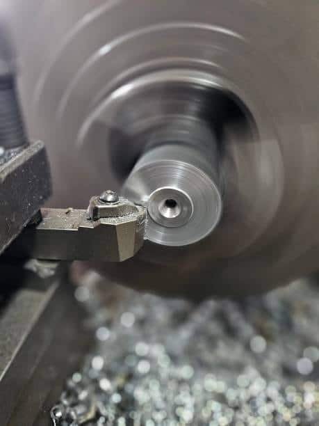 Close-up of a lathe tool cutting a rotating metal rod