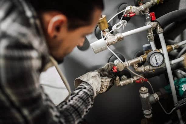 Technician adjusting valves and pressure gauges during machine fixture setup