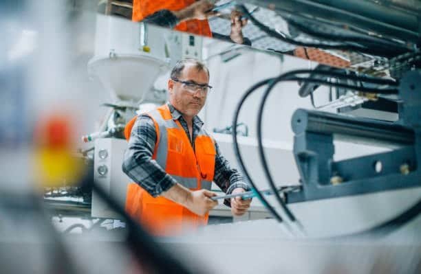 Technician monitoring a CNC milling machine setup during manufacturing operation