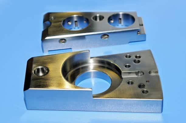 Close-up view of CNC-machined aluminum part on blue background for prototype runs