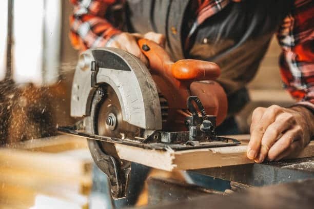 Close-up view of a handheld circular saw cutting through wood during workshop activity
