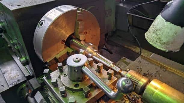 Close-up of a manual lathe setup with handwheel and fixed chuck