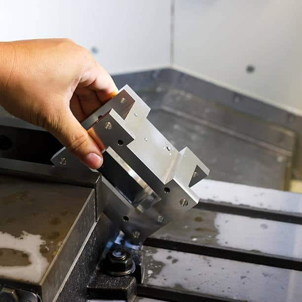 Operator removing a machined metal part from a CNC fixture after precision milling