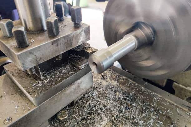 Metal rod turning on a lathe with cutting insert and metal shavings