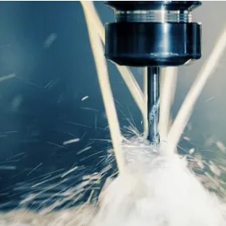 Multi-axis CNC milling cutter cutting metal with coolant spray and sparks illustrating precision machining.