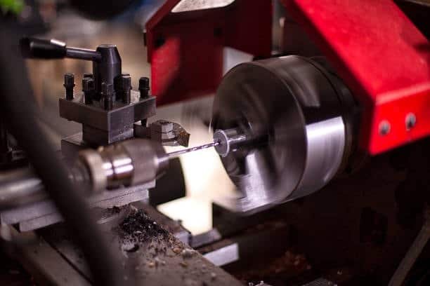 Compact lathe machine drilling a hole at the center of a rotating shaft