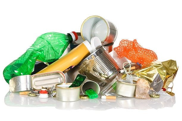 Collection of mixed plastic waste including PET bottles, cans, and packaging for recycling