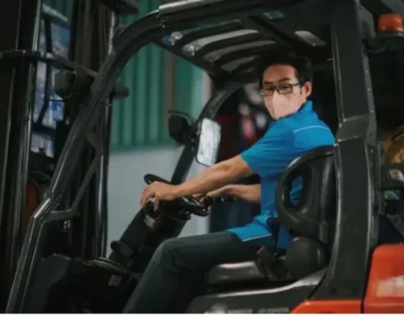 Project manager operating a forklift in a warehouse, ensuring timely mold delivery and logistics management.