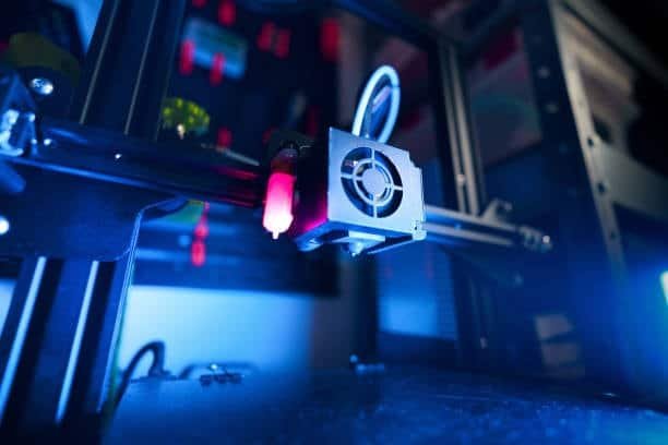 Close-up of 3D printer extruder working under blue light