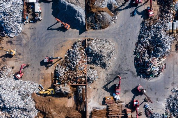 Aerial view of industrial recycling yard with machinery and sorted plastic and metal waste