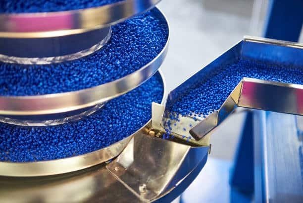 Blue plastic pellets loaded for pre-melting in industrial processing equipment