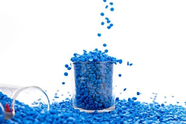 Blue TPE granules being poured into a transparent glass, highlighting their clean, non-toxic characteristics.