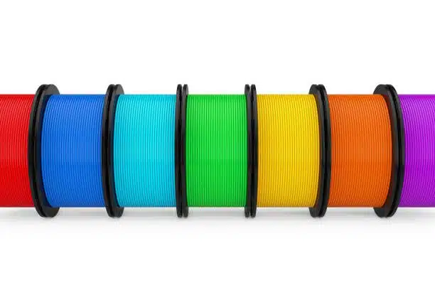Colorful polypropylene and polycarbonate filament spools side by side, highlighting material variety.