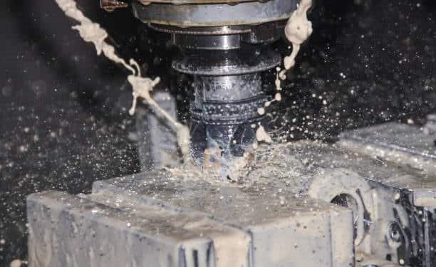CNC milling machine cutting metal with coolant spraying at high speed