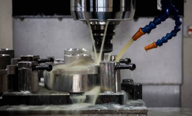 CNC machine milling metal component with dual coolant hoses in operation