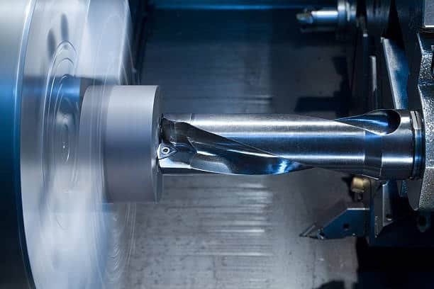 Precision CNC turning showing a cutting tool shaping a cylindrical metal part